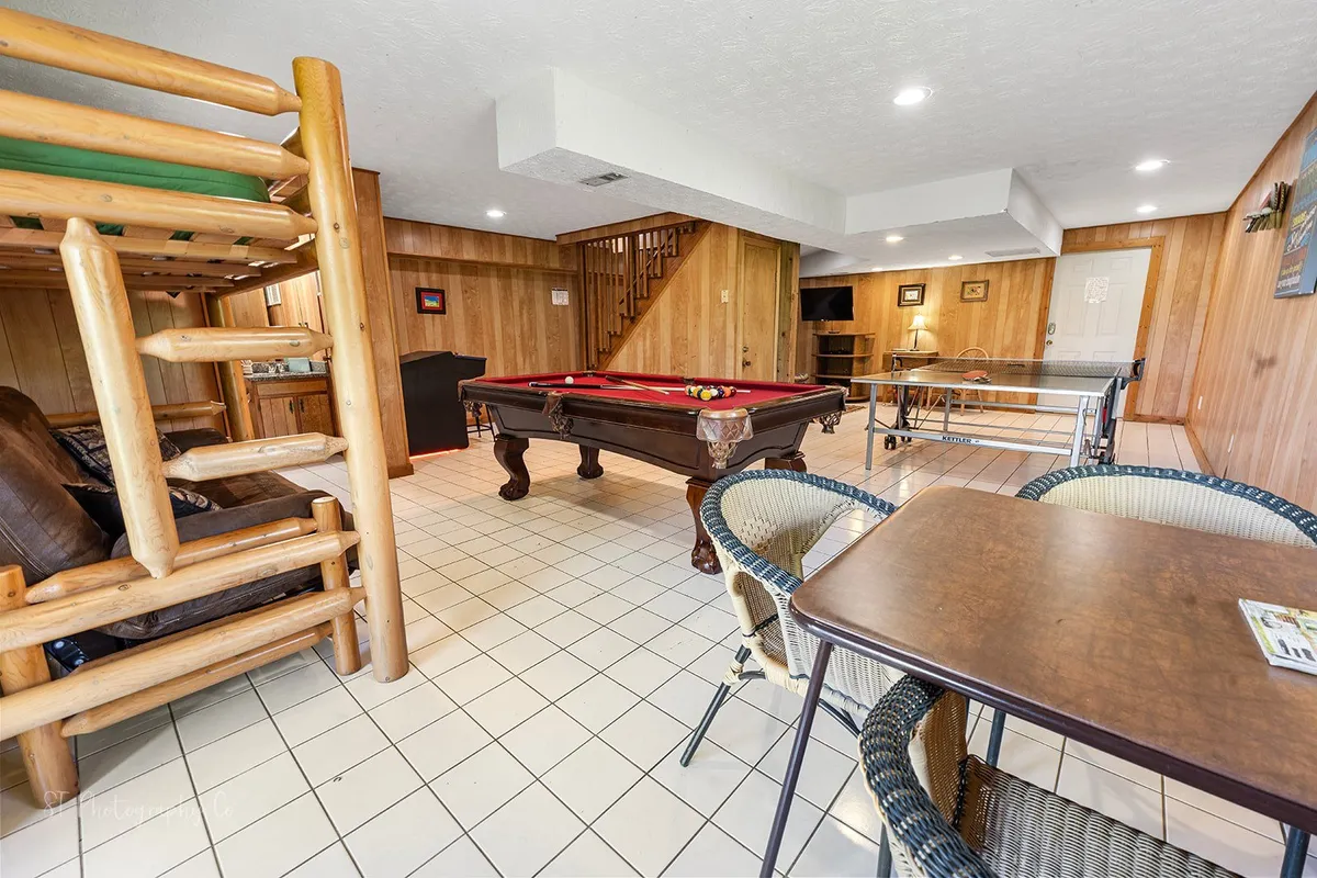 An entertainment room featuring a pool table, bunk beds, a relaxed seating area, and a dining table. The versatile space is ideal for group activities, whether it's hosting a game night, sharing laughs, or celebrating special occasions.