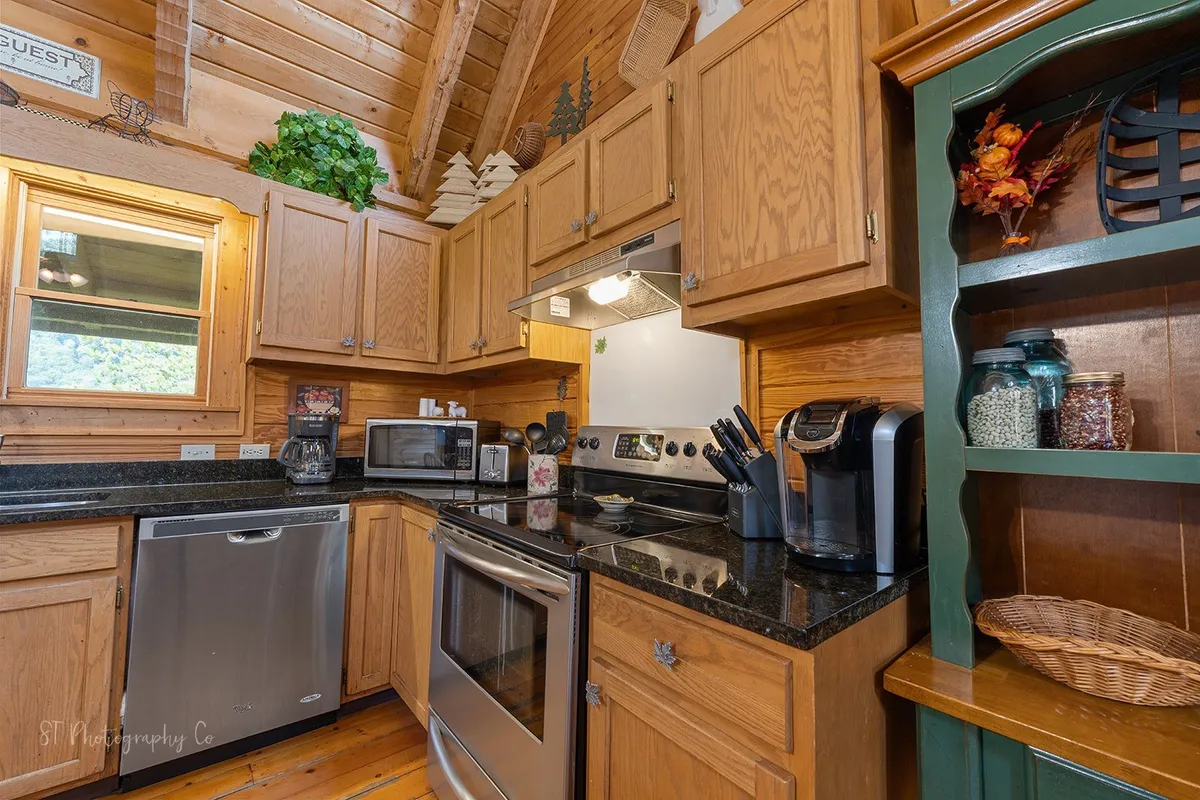 A bright, welcoming kitchen with a large black granite island, modern appliances, and warm wooden cabinetry. The space is set up for cooking, casual gatherings, and family meals, with ample seating and a friendly, communal atmosphere.