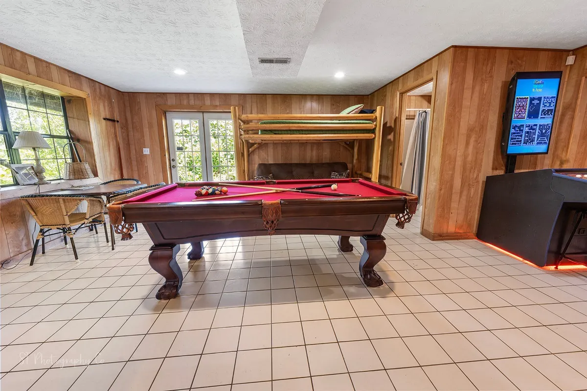 This space features a classic pool table, a bunk bed for extra guests, and a casual dining area adjacent to a gaming console setup. The room is designed for multi-activity fun, serving as a central hub for family game nights, celebrations, and friendly competitions.